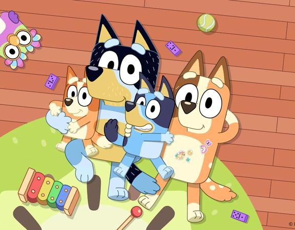 A frame from the popular children's animated television series 'Bluey'. Bluey and her family lie together on the living room floor with a few toys scattered around.