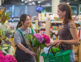 Staff member handing a bouquet of flowers to a customer inside Moore Wilsons.