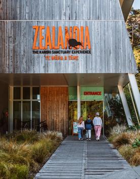 Three people walk toward the Zealandia building entrance.