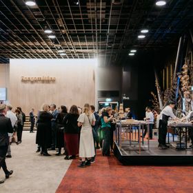 Inside Tākina Wellington Convention & Exhibition Centre at the opening event. There is food catering and many people are mingling in formal wear.