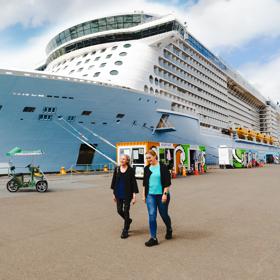 Two people walking next to a cruise ship on the Wellington waterfront.