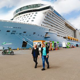 Two people walking next to a cruise ship on the Wellington waterfront.