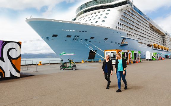 Two people walking next to a cruise ship on the Wellington waterfront.
