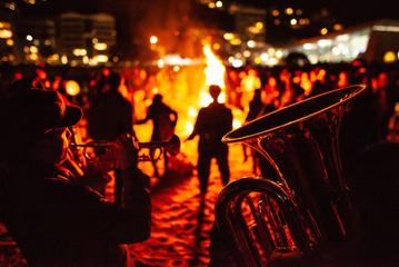 Brass musicians perform at a bonfire on the beach.