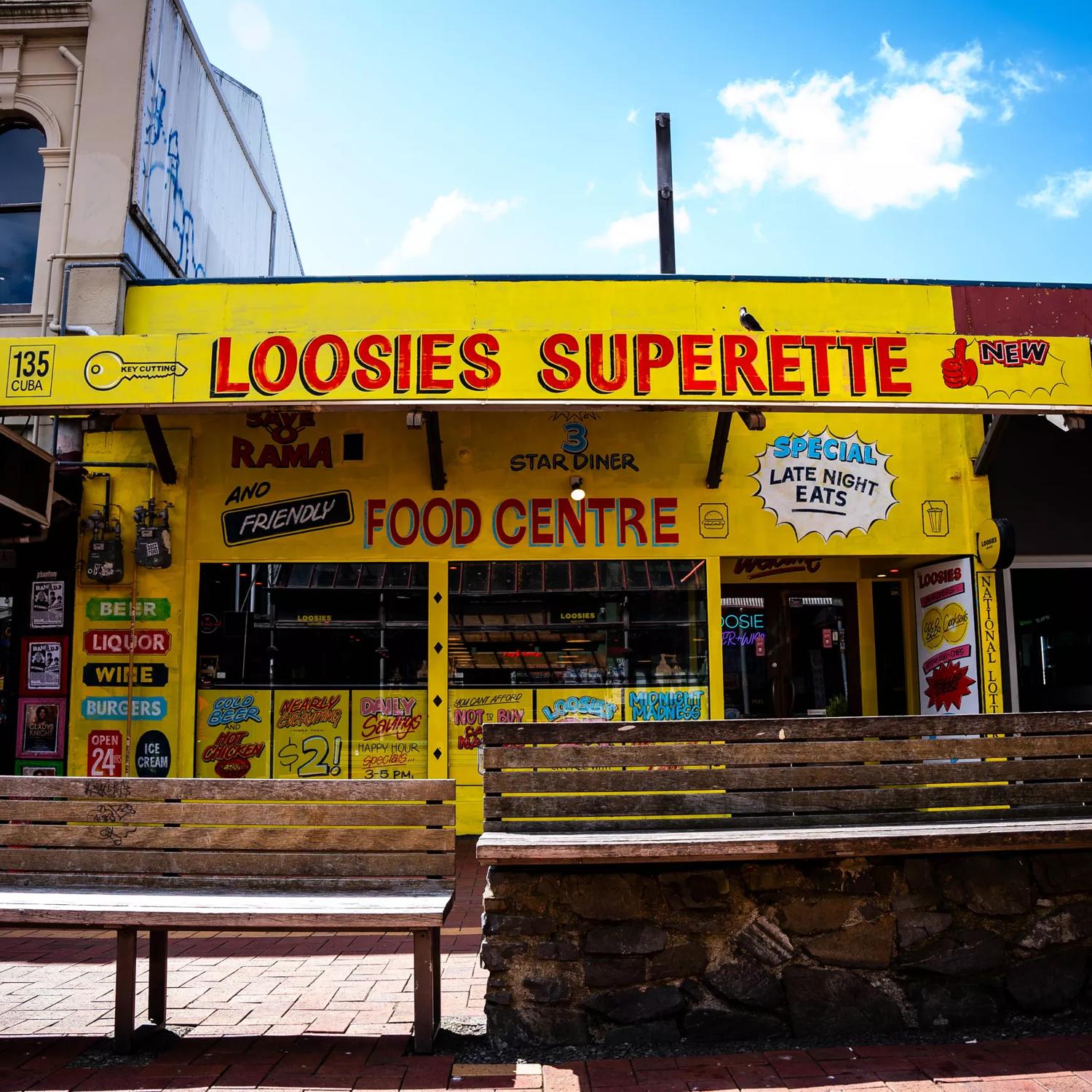 The storefront of Loosies Superette. It's a small restaurant, panted in yellow with retro lettering. 