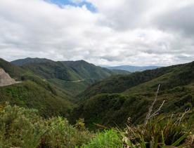 The screen location of Remutaka Summit, wit views of surrounding peaks, lush green bush and steep roads cut into the sides of the mountains.