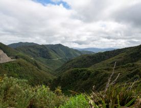 The screen location of Remutaka Summit, wit views of surrounding peaks, lush green bush and steep roads cut into the sides of the mountains.