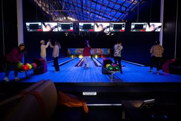 Group of people bowling in luminescent light at Daytona Adventure Park in Brewtown, Upper Hutt.