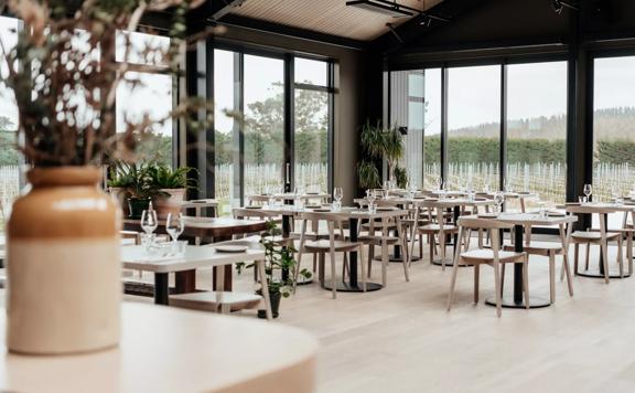 Inside the Banquet room at The Runholder, the floor, walls, and high-ceiling roof are a light wood with black accents in the lights and fixtures.