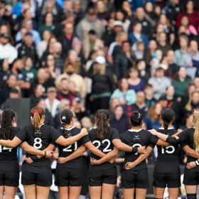 Black Ferns rugby players standing in a line with their hands crossing over each other.