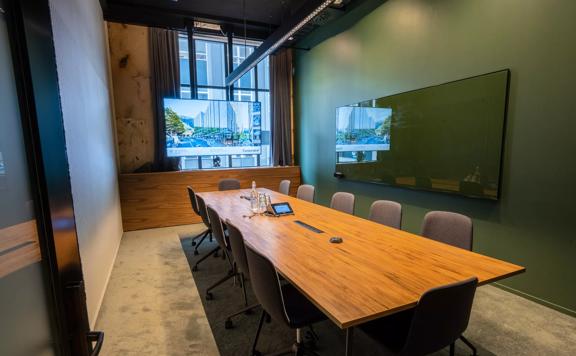 A meeting room at Generator on Waring Taylor Street has green walls, a wooden table surrounded by 12 chairs.