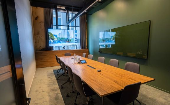 A meeting room at Generator on Waring Taylor Street has green walls, a wooden table surrounded by 12 chairs.