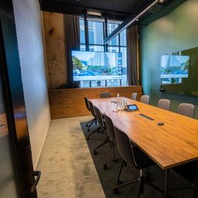 A meeting room at Generator on Waring Taylor Street has green walls, a wooden table surrounded by 12 chairs.