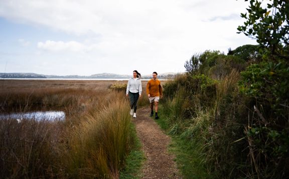 Two people walking on a dirt section of Te Ara Piko.