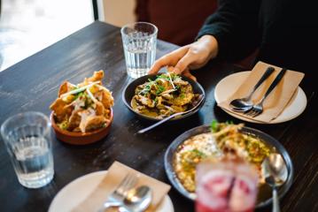 Close up of dishes served at Chaat Street with hands.