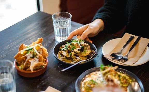 Close up of dishes served at Chaat Street with hands.