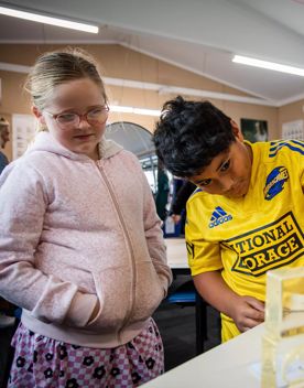 Two classmates look at a fish skeleton during a House of Science learning session.