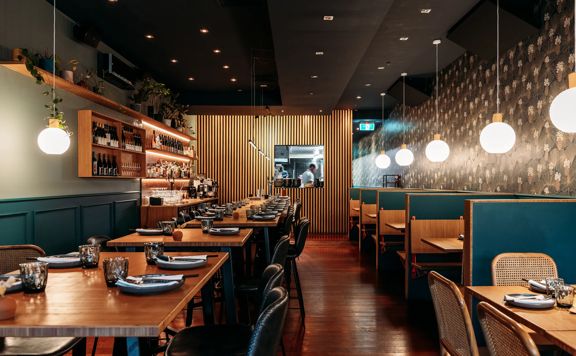 The interior of Koji in Mount Victoria. There is a black roof  is moody, with lantern lights and leather and blue velvet bench seats.