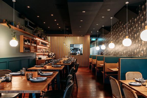 The interior of Koji in Mount Victoria. There is a black roof  is moody, with lantern lights and leather and blue velvet bench seats.