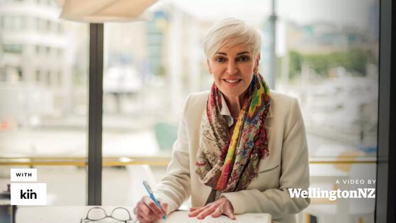 Wendy Alexander smiling at the camera while holding a pen in one hand.