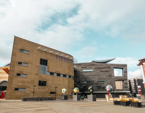 The Large concrete exterior of Te Papa, with 4 large globe statues outside.