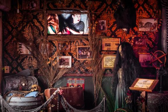 A spooky set up of props inside Fear Factory, including a witch and cobwebs.