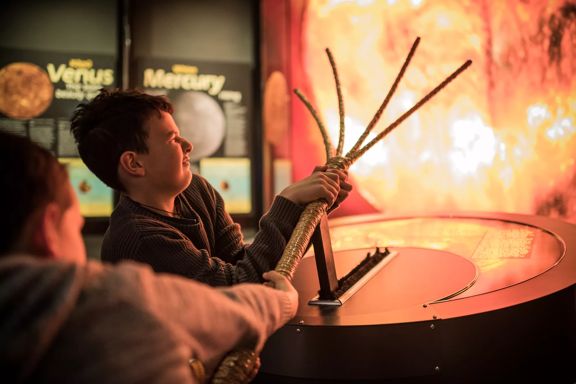 Two boys pull Māui's rope to slow down the sun at Space Place.