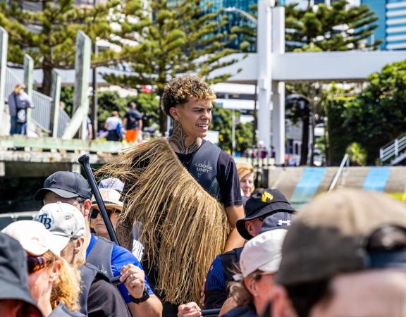 A waka experience guide stands in the middle of people rowing at Whairepo Lagoon on Wellington's waterfront.