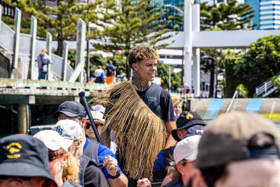 A waka experience guide stands in the middle of people rowing at Whairepo Lagoon on Wellington's waterfront.