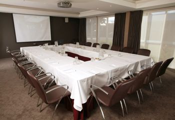 Square room with 16 leather chairs around a rectangle table.