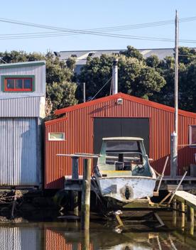The Petone boat ramp, Hikoikoi,  with colourful boat sheds and boats in the morning sun.