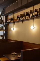 A booth and table of Rosella restaurant. Wine bottles line a shelf high above the seats.