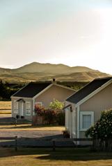 2 accommodation houses in front with rose bushes surrounding, and Hills in the background.