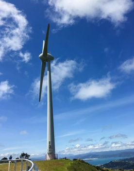 A large wind turbine perched on the edge of a hill.