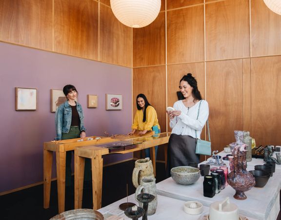 Three friends are shopping for pottery.