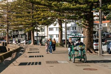 Oriental Parade, where a croc bike is seen going down the path and people walking along the waterfront.