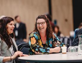 Two people at a conference table smiling at each other while networking