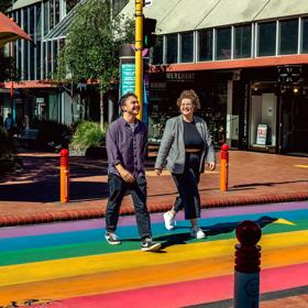 Two people cross the street at the Rainbow Crossing on Cuba Street in Te Aro, Wellington.