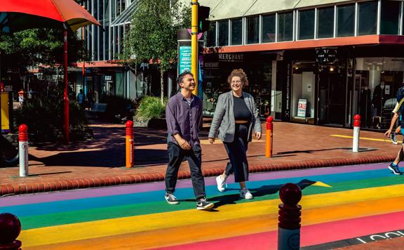 Two people cross the street at the Rainbow Crossing on Cuba Street in Te Aro, Wellington.