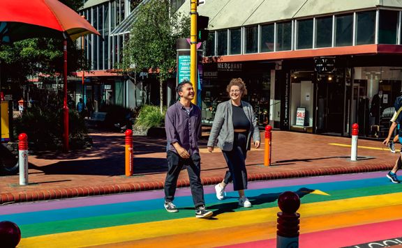Two people cross the street at the Rainbow Crossing on Cuba Street in Te Aro, Wellington.