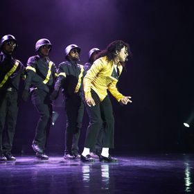 A Michael Jackson impersonator performs with four back up dancer.
