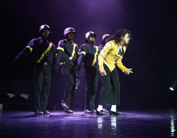 A Michael Jackson impersonator performs with four back up dancer.