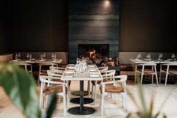 The restaurant inside of The Runholder. A large fireplace warms the room, and wine glasses sit on each table.