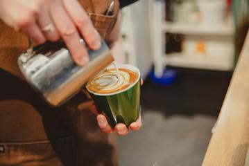 A barista pours steamed milk into a coffee at Twenty Eight, a café in Lower Hutt.