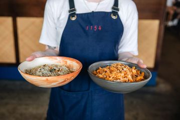 Close-up of waiter's hands holding two pasta bowls at 1154 Pastaria on Cuba Street.