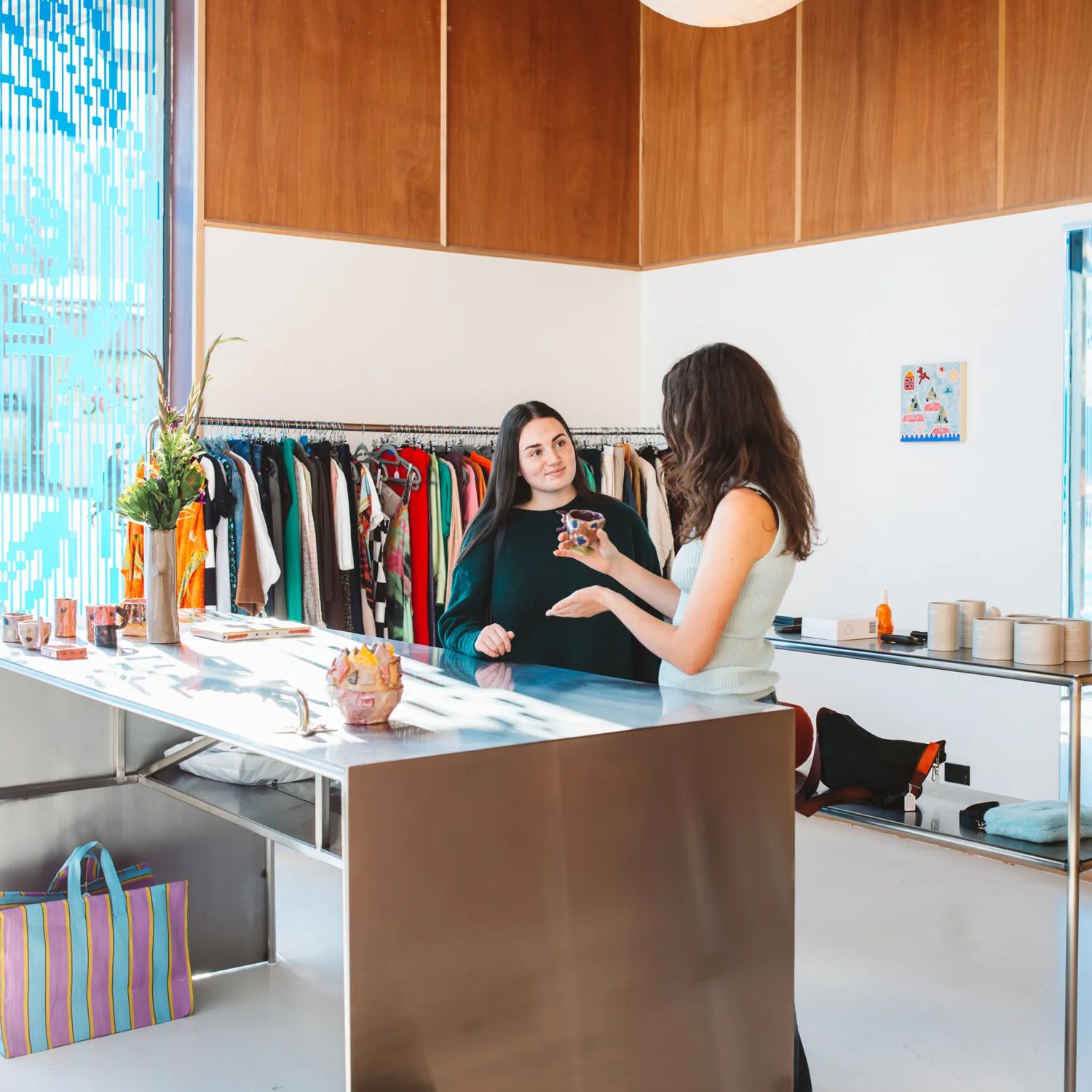 The interior of Sully's has a large metal counter with clothes racks against the wall. Two people stand at the counter.