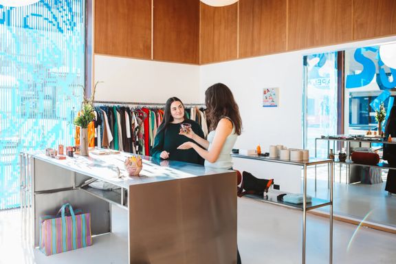 The interior of Sully's has a large metal counter with clothes racks against the wall. Two people stand at the counter.
