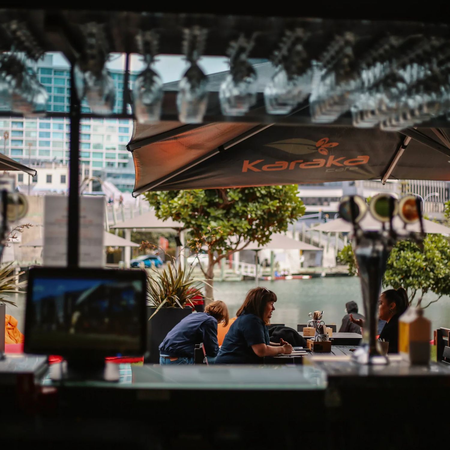 Customers seated at outside tables at Karaka Cafe at Te Wharewaka o Pōneke.