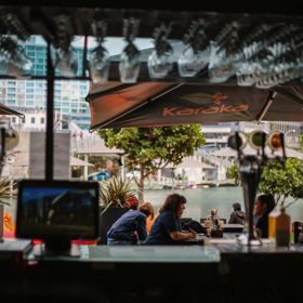 Customers seated at outside tables at Karaka Cafe at Te Wharewaka o Pōneke.