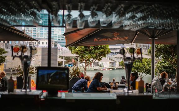 Customers seated at outside tables at Karaka Cafe at Te Wharewaka o Pōneke.